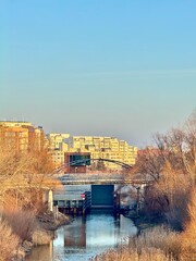 view of a Vistula bridge with autumn-colored trees and Warsaw buildings in the background
