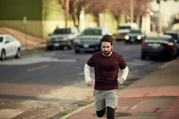 Fototapeta premium Young man jogging in a town on a street