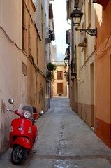 Red scooter parked in narrow alley in european town. Xativa, Spain. © vanilla_jo