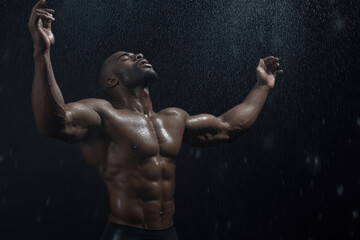 Fototapeta premium A man with a muscular body is standing in the rain