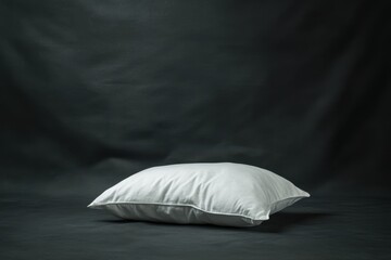 A Fluffy White Pillow Rests on a Solid Dark Gray Background