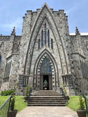 Igreja Matriz de Nossa Senhora de Lourdes, also known as Rock Cathedral, of the city of Canela, Rio Grande do Sul, Brazil. English neogothic style. Side entrance view. Interior stained glass visible.