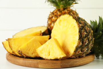 Whole and sliced fresh ripe pineapples on white table, closeup