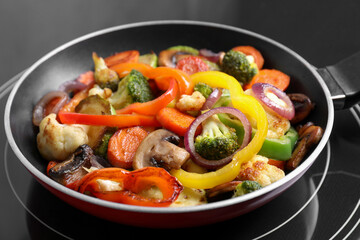 Frying pan with mix of vegetables and mushrooms on cooktop, closeup