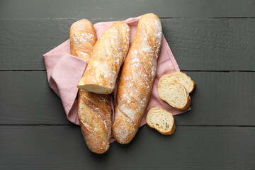 Cut fresh baguettes on grey wooden table, top view
