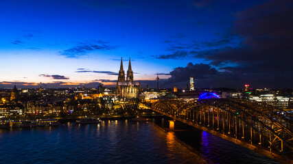 Fototapeta premium Night city skyline aerial view of Cologne in Germany from above right after sunset. Photo showing famous bridge and famous Church-Dom