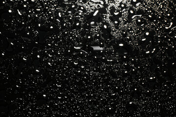 Water drops on black glass surface, top view