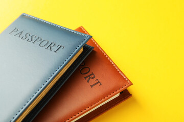Passports in color covers on yellow background, closeup. Space for text
