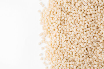 Pile of plastic granules on white background, top view. Space for text