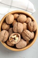 Fresh walnuts in bowl on gray table, top view