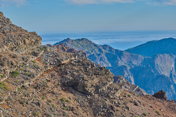 Mountains, volcano and outdoor in nature, sky and island with geology, rocks and summer in environment. Cliff, stone and sunshine on hill with landscape, trekking and tourism in La Palma, Spain