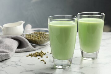 Fresh mung bean juice in glasses and seeds on white marble table