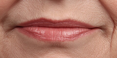 Fototapeta premium Close-up view of a woman's lips showcasing natural texture and soft color in a neutral background