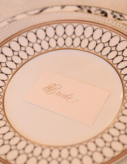 Elegant place setting for bride at wedding reception featuring ornate plate and name card