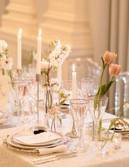 Elegant dining table adorned with flowers and candles for a special event in a beautifully lit interior