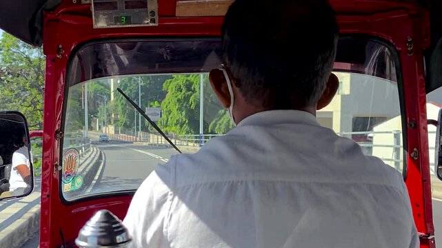Tuk-tuk driver navigating through a busy urban street. Popular and affordable three-wheeler transportation commonly used by locals and tourists in city traffic in Southeast Asia.