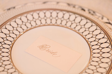 Elegant place setting for bride at a wedding reception with intricately designed plate and name card