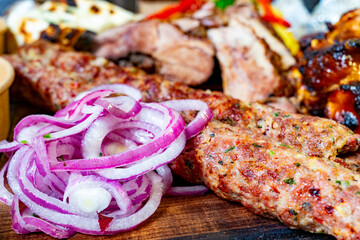 Grilled meats and onions served on a wooden platter at a barbecue