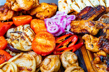 Grilled meats and veggies on a wooden platter at summer BBQ