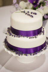 Elegant white wedding cake decorated with lavender and purple ribbon