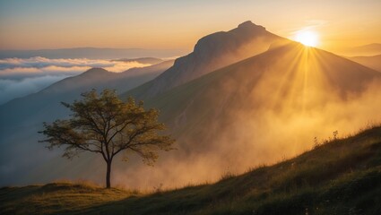Serene scenery - the outline of towering mountains with an orange hue at a vibrant golden yellow sunset, shrouded in mist, with a solitary tree catching the sun's rays on the hillside during a summ...