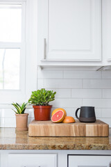 Modern kitchen counter with plants, grapefruit, and a black mug