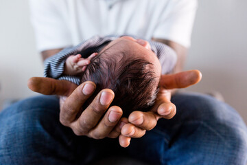 Fototapeta premium Father gently cradling a newborn baby's head in his hands