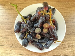 A bunch of Black Sweet Sapphire Grapes or Witch Grapes seedless elongated shaped with a fruit tip...