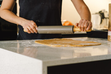 A woman in casual attire prepares dough for baking. She looks pleased and focused, enjoying the baking process in a light-filled kitchen.