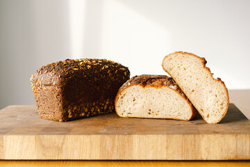 Sourdough bread, freshly baked and still warm, are stacked on a wooden surface. The bread are covered in seeds sesame and sunflower, adding a rustic and flavorful touch.