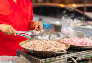 Vender grilled pork in a pan on a stove.
