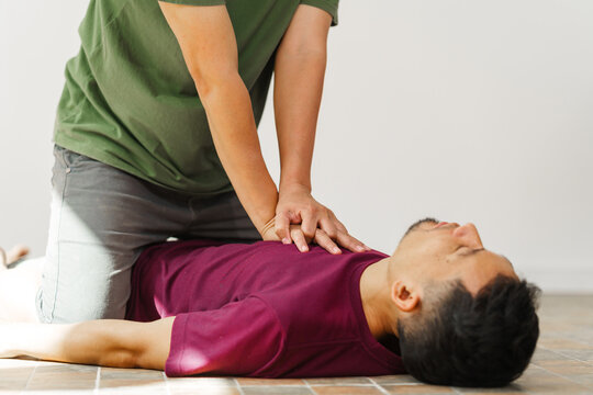 A woman performs chest compressions, administering CPR to an unconscious young man, demonstrating life-saving skills, emergency response, first aid, and medical assistance in a critical situation