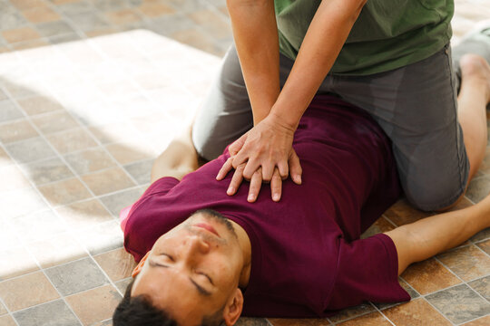 A woman performs chest compressions, administering CPR to an unconscious young man, demonstrating life-saving skills, emergency response, first aid, and medical assistance in a critical situation - Powered by Adobe