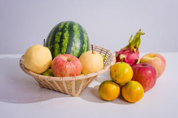 A rattan basket filled with colorful, fresh fruits is placed on a table. Fruits, rich in fiber, vitamins, and antioxidants, are essential for health, promoting body function and slowing down aging.