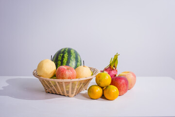 A rattan basket filled with colorful, fresh fruits is placed on a table. Fruits, rich in fiber, vitamins, and antioxidants, are essential for health, promoting body function and slowing down aging.
