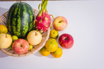 A rattan basket filled with colorful, fresh fruits is placed on a table. Fruits, rich in fiber, vitamins, and antioxidants, are essential for health, promoting body function and slowing down aging.