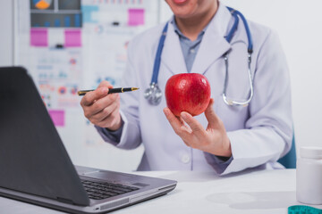 A male nutritionist works at his desk, discussing the benefits of eating fruit. He analyzes diets...