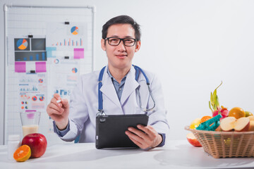 A male nutritionist works at his desk, discussing the benefits of eating fruit. He analyzes diets...