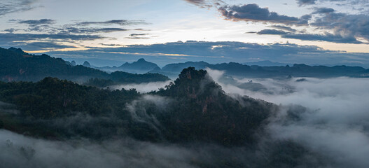 Aerial view A breathtaking view of dawn breaking over a misty mountain landscape, with layers of fog and vibrant colors painting the horizon. The serene atmosphere and natural beauty