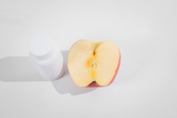 A supplement bottle and a fresh apple placed on the table, symbolizing health and nutrition, representing dietary choices, wellness, and natural or medical supplementation for a balanced lifestyle