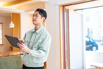 タブレットを持ち確認する作業着を着た男性 © ponta1414
