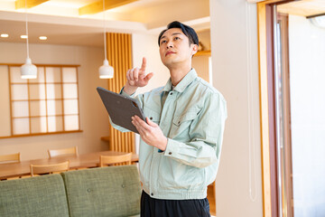 タブレットを持ち確認する作業着を着た男性