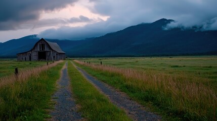 Serene rural landscape featuring a rustic barn along a gravel path with mountains in the background