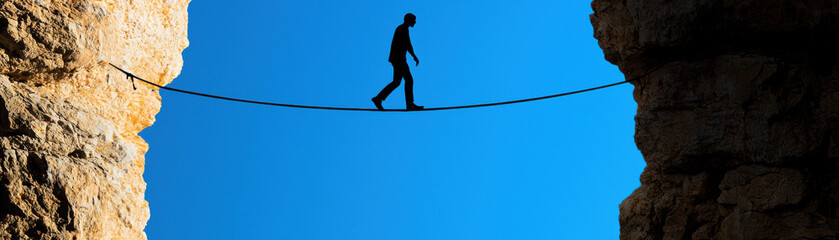 Conversion disorder psychology cognitive FND. A person balances on a tightrope between two cliffs against a blue sky.