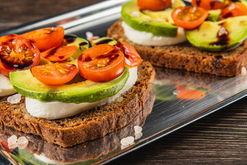 Delicious open-faced sandwich with avocado and cherry tomatoes on dark bread
