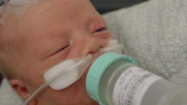 POV of a Newborn Baby Drinking from a Bottle While at the NICU While Being Held
