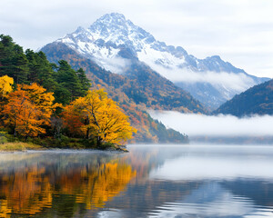 Obraz premium Autumnal lake reflecting snow-capped mountain, misty morning