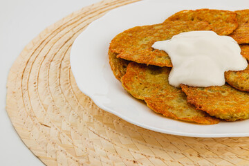 Savory potato pancakes served with creamy dip on a woven placemat