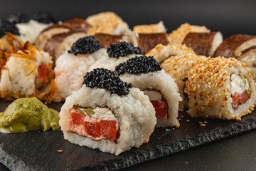 Sushi rolls on a black slate platter featuring fresh ingredients and toppings