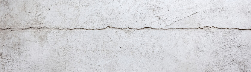 Obraz premium Faded white concrete wall with textured surface and visible cracks